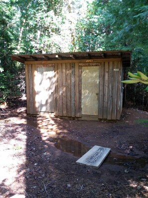 Una estructura de madera con una puerta que dice 'WOMEN' y una puerta más pequeña que dice 'BRACE'.