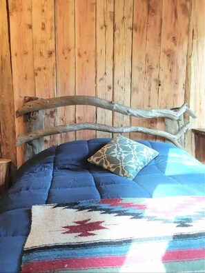 Ein Bett mit blauer Steude, einem gemusterten Kissen und einer Decke mit rotem Sternmuster.