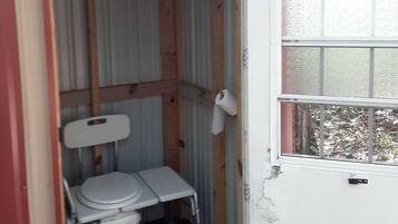 Un baño pequeño y cerrado con inodoro, ventana y puerta.