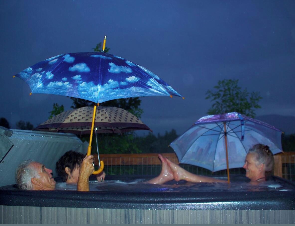 A hot tub with people relaxing under umbrellas.