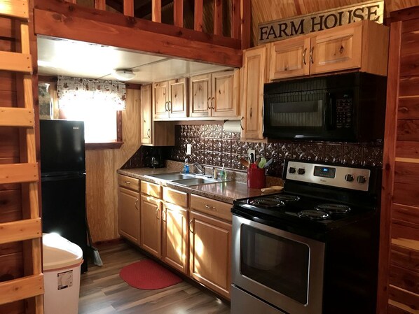 A kitchen with wooden cabinets, a stove, a microwave, and a refrigerator.