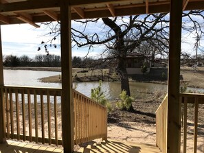 A wooden deck with a view of a river and a tree. - Cozy Cabin Rental on a Winery for a Romantic Weekend Getaway in Oklahoma (Allen)