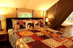 Een bed met beddengoed met een patroon, een hoofdbord en een raam met gordijnen.