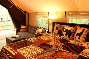 Una habitación con tienda de campaña, una cama, un sofá, una lámpara y vistas al exterior.