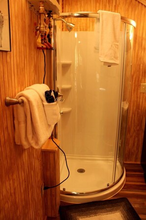 A shower with a glass door, a towel rack, and a wooden wall. - African-Themed Safari Tent for Glamping in West Virginia (Hico)