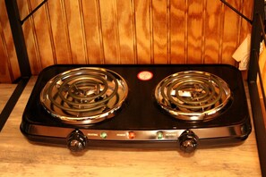 A black electric stove with two burners and control knobs for heating and power. - African-Themed Safari Tent for Glamping in West Virginia (Hico)