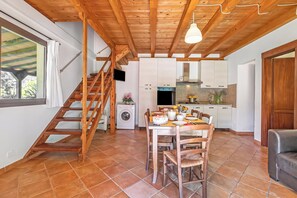 A spacious kitchen with a dining area, wooden staircase, and a large window. - Relaxing Countryside Apartments Near Cecina Sea (Cecina)