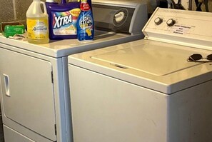 A front-loading washing machine with detergent bottles on top.