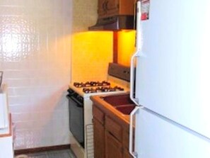 Une cuisine de taille réduite, équipée d’une cuisinière, d’un four et d’un réfrigérateur.