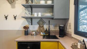 A compact kitchen with a refrigerator, a sink, and a window.