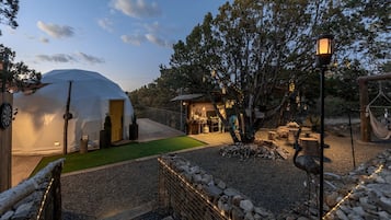 A yurt with a door, a small wooden structure, and a hammock.