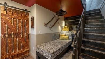 A bedroom with a bed, a wooden door, a staircase, and a fan.