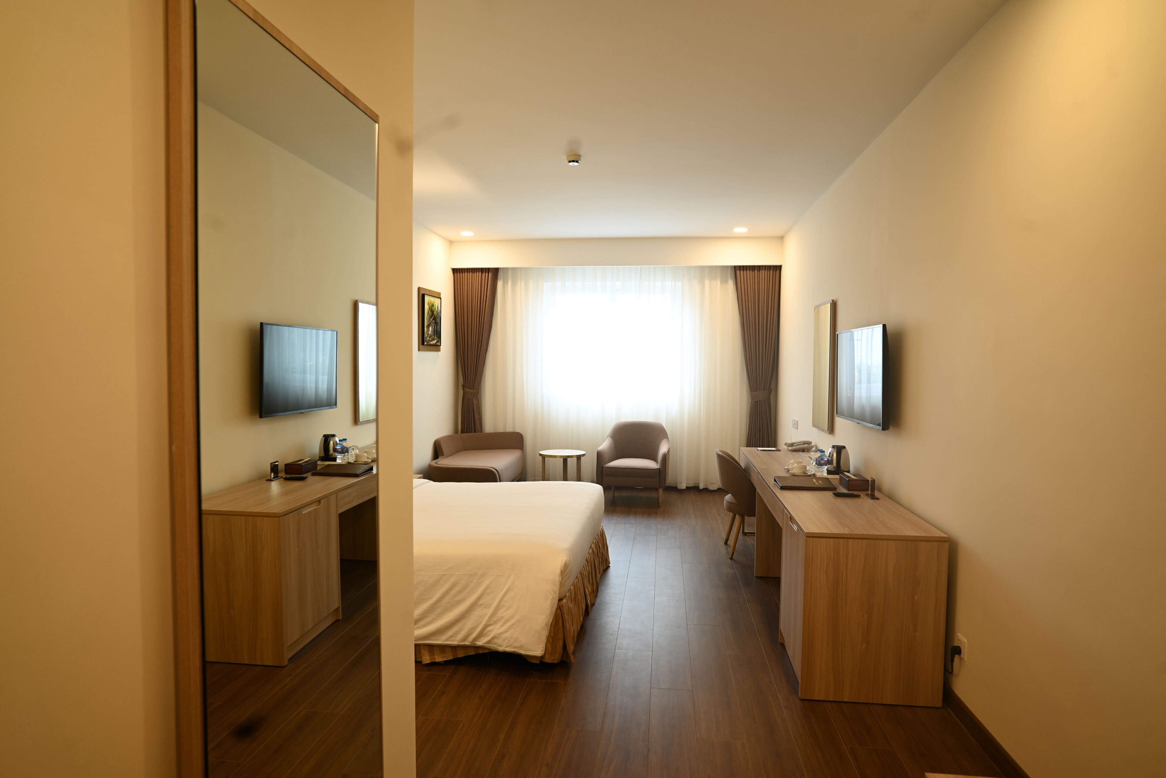 Une chambre d’hôtel équipée d’un lit, d’un bureau, d’une chaise, d’une télévision et d’une fenêtre avec des rideaux.
