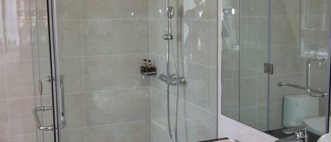 A modern bathroom with a glass-enclosed shower, a white sink, and a large mirror.