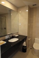 Ein modernes Badezimmer mit großem Spiegel, Waschbecken, Toilette und Dusche.