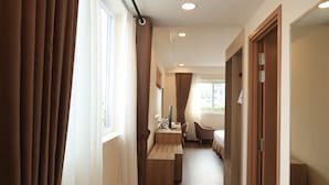 A hotel room with a desk, chair, bed, and a view of the outdoors. - Sai Gon Da Lat Premium (Xuan Huong - Da Lat)