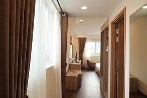 A hotel room with a desk, chair, bed, and a view of the outdoors. - Sai Gon Da Lat Premium (Da Lat)
