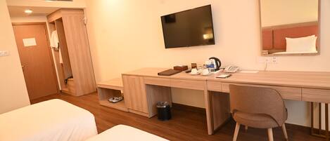 A hotel room with two beds, a desk with a chair, a TV, and a mirror.