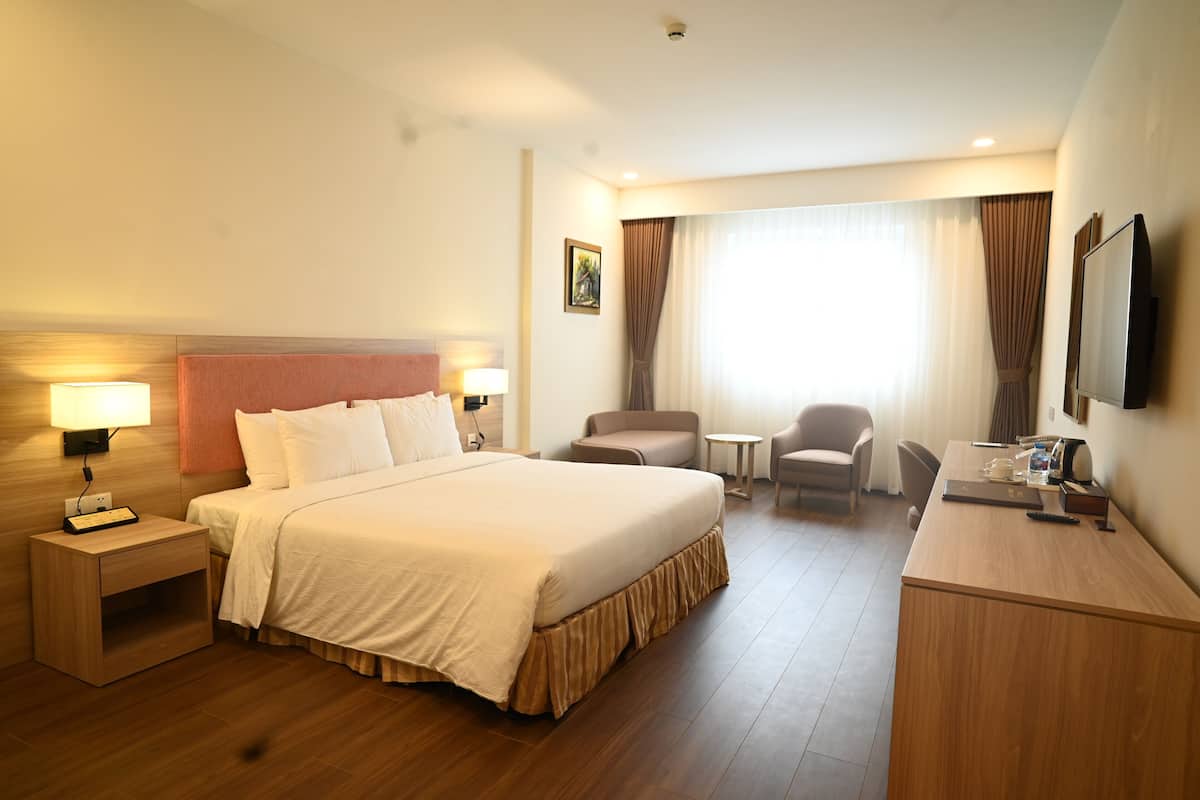 Une chambre d’hôtel comprenant un lit, des tables de chevet, un bureau, une chaise et un téléviseur.