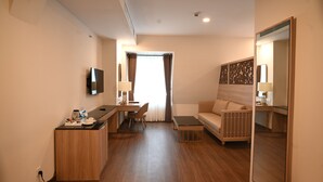 A hotel room with a kitchenette, a sofa, a TV, and a large mirror. - Sai Gon Da Lat Premium (Xuan Huong - Da Lat)