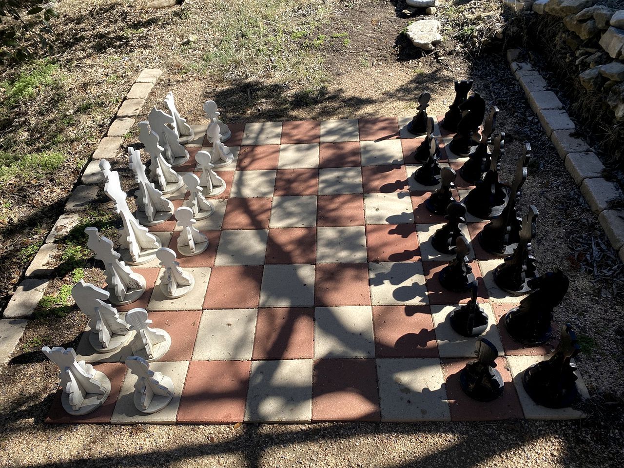 A chessboard set outdoors with pieces arranged for a game.
