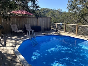 A swimming pool with a wooden deck, a ladder, and two lounge chairs. - Wimberley Romance: Escape to a Cozy Cabin Nestled in Nature, TX (Wimberley)