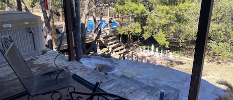 Un espacio al aire libre cubierto con un jacuzzi, una terraza de madera y sillas de metal.