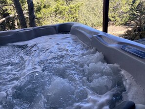 A hot tub with water, surrounded by trees. - Wimberley Romance: Escape to a Cozy Cabin Nestled in Nature, TX (Wimberley)