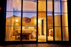 A cozy room with a bed, a wooden wall, and a window with curtains. - Stunning Design Rental Incredible for a Luxury Escape in Lone Pine, California (Lone Pine)