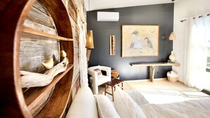 A cozy room with a wooden barrel shelf, a white sofa, a painting on the wall, and a bench.
