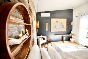 Una stanza accogliente con uno scaffale in legno a forma di botte, un divano bianco, un quadro appeso e una panca.