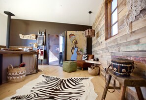 A rustic interior with a wooden floor, a zebra print rug, a painting of a woman, and a drum. - Stunning Design Rental Incredible for a Luxury Escape in Lone Pine, California (Lone Pine)
