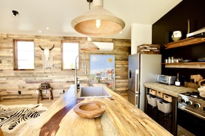 Una cucina rustica con un piano di lavoro in legno, un lavello, un lampadario e un frigorifero.
