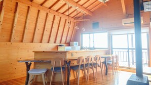 Een houten interieur met een eethoek, stoelen, een tafel, een hanglamp en een raam.