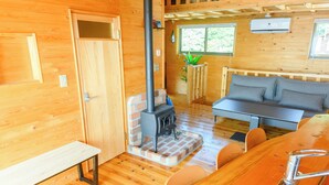 Een houten interieur met een bank, een houten zitbank, een tafel en een open haard.