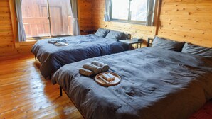 Een kamer in chaletstijl met twee bedden, houten vloeren en grote ramen.