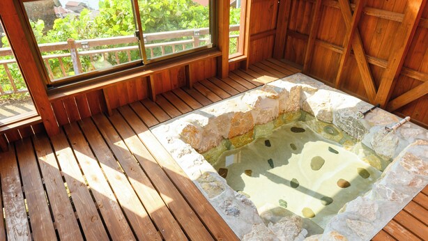 Een houten terras met een jacuzzi, houten wanden en een raam met uitzicht op groen.