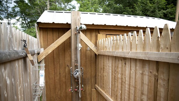 Une structure en bois, dotée d’un portail en métal, d’une étagère en métal et d’un tuyau en métal.