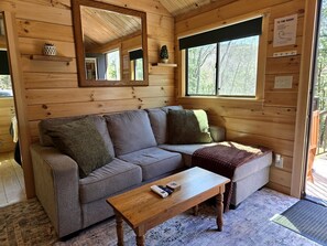 Ein Holzblockbau-Innenraum mit Sofa, Couchtisch, Spiegel und Fenster.