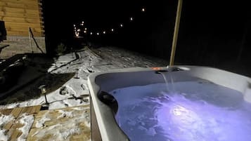 A hot tub with a wooden deck and snow on the ground.