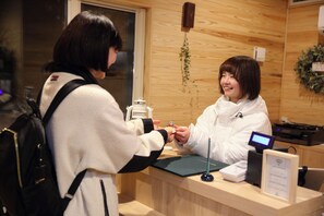 A reception desk with a digital display, a clipboard, and a small plant on the wall. - yamagata glam (Murayama)