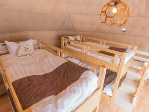 Una habitación tipo tienda de campaña acogedora con dos literas, un osito de peluche en la cama inferior y una lámpara colgante.