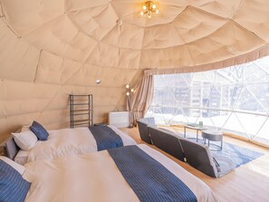 Una habitación con carpa, dos camas, una mesita y una silla.