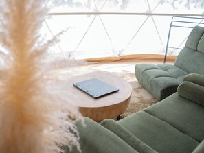 Un intérieur moderne avec un canapé vert, une table ronde en bois et un livre intitulé « INFORMATION ».