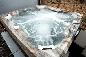A hot tub with a marble exterior, control panel, and seating area. - Lake Cabin with Hot-Tub and Deck in Pennsylvania (Lake Ariel)