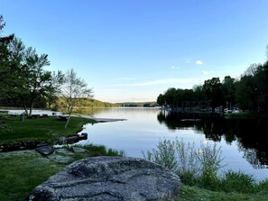 Een kalm meer met een picknickplaats en een grote rots op de voorgrond.