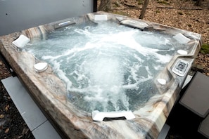 Ein Whirlpool mit Marmorverkleidung, Bedienfeld und Sitzbereich.