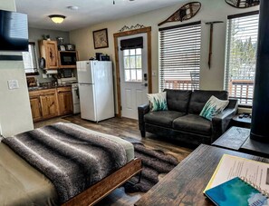 A compact living space with a kitchenette, a sofa, a bed, and a dining table.