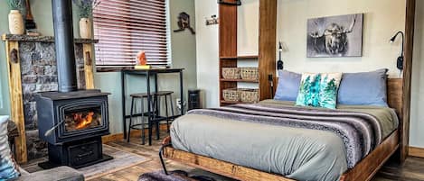 Une chambre confortable avec un lit, une cheminée, un bureau et une étagère suspendue.