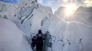 Un étroit passage enneigé entre des montagnes recouvertes de neige, où l’on voit une personne qui marche.